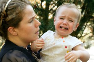 Toddler tantrums and child behavior - image of a toddler pulling away from parents